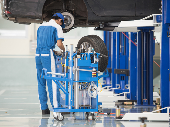 This image shows a commercial vehicle repair shop. There is a car on a lifter.