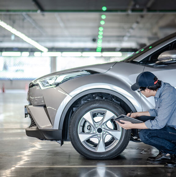 This image shows a man checking the tire of a car.
